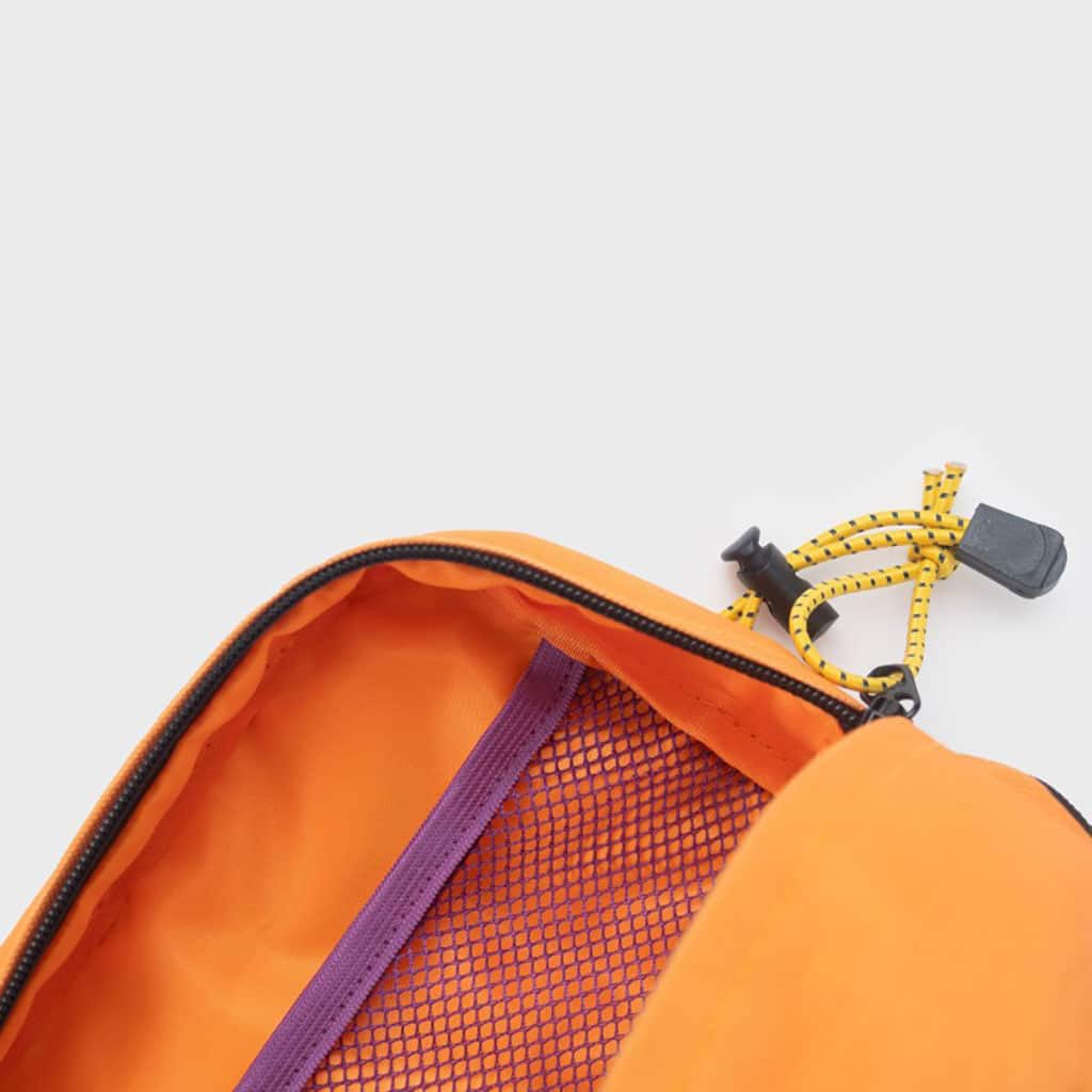 Une trousse de toilette en polyester recyclé orange et taupe Billybelt, zoom sur l'intérieur sur fond blanc